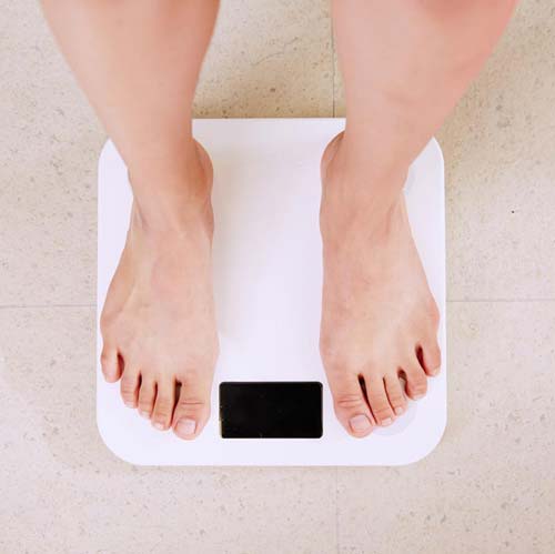 View of bare feet on a bathroom scale.