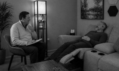 Paul in session with older man who is reclining, under hypnosis.