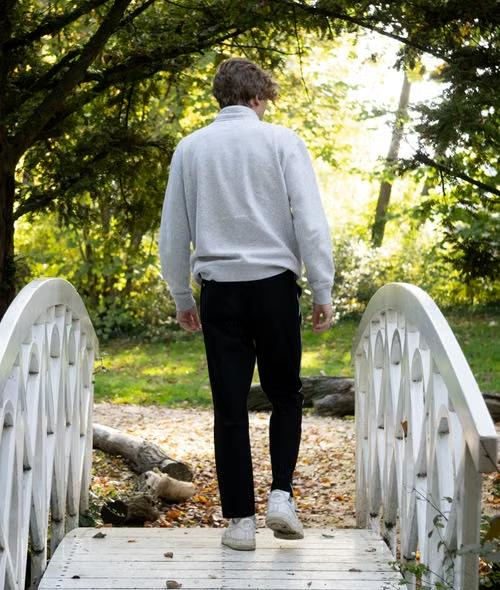 Back-view of man walking over small bridge on graveled pathway.